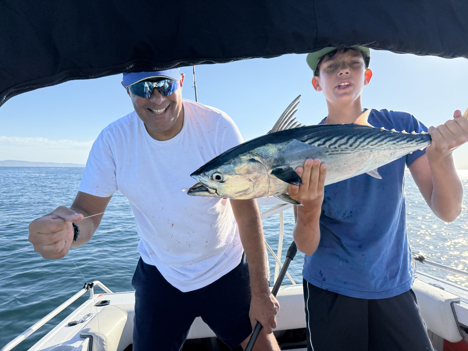 Patrick and his son on a boat, his son holding up a large fish they just caught